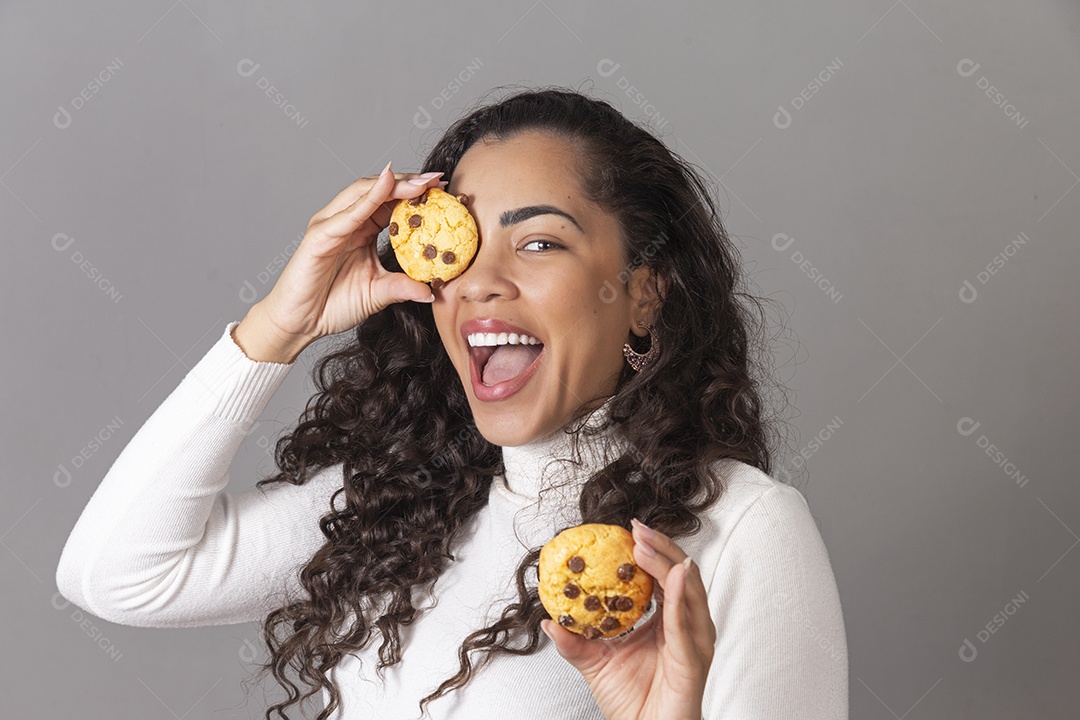 Linda mulher sorridente segurando biscoito sobre o olho em um fundo isolado