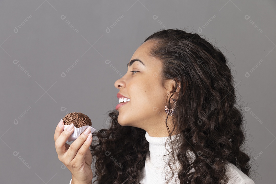 Linda mulher sorridente segurando um cupcake sobre fundo isolado.