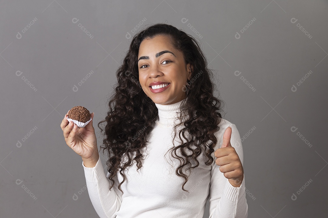 Linda mulher fazendo sinal positivo segurando um cupcake sobre fundo isolado