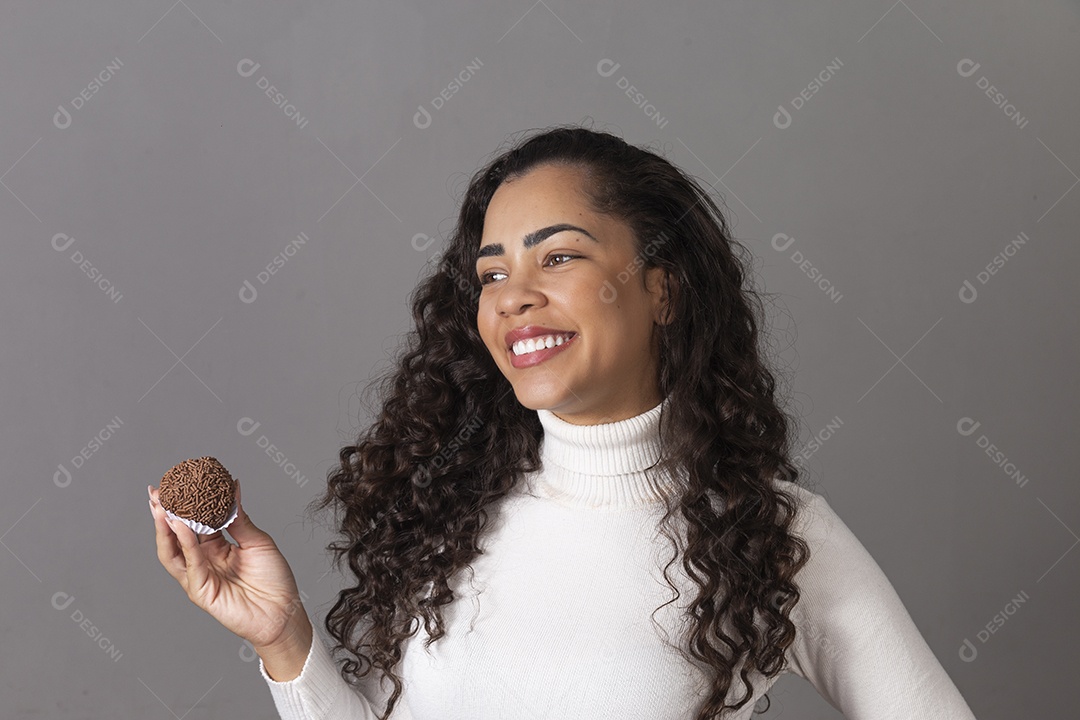 Linda mulher sorridente segurando cupcake sobre fundo isolado.