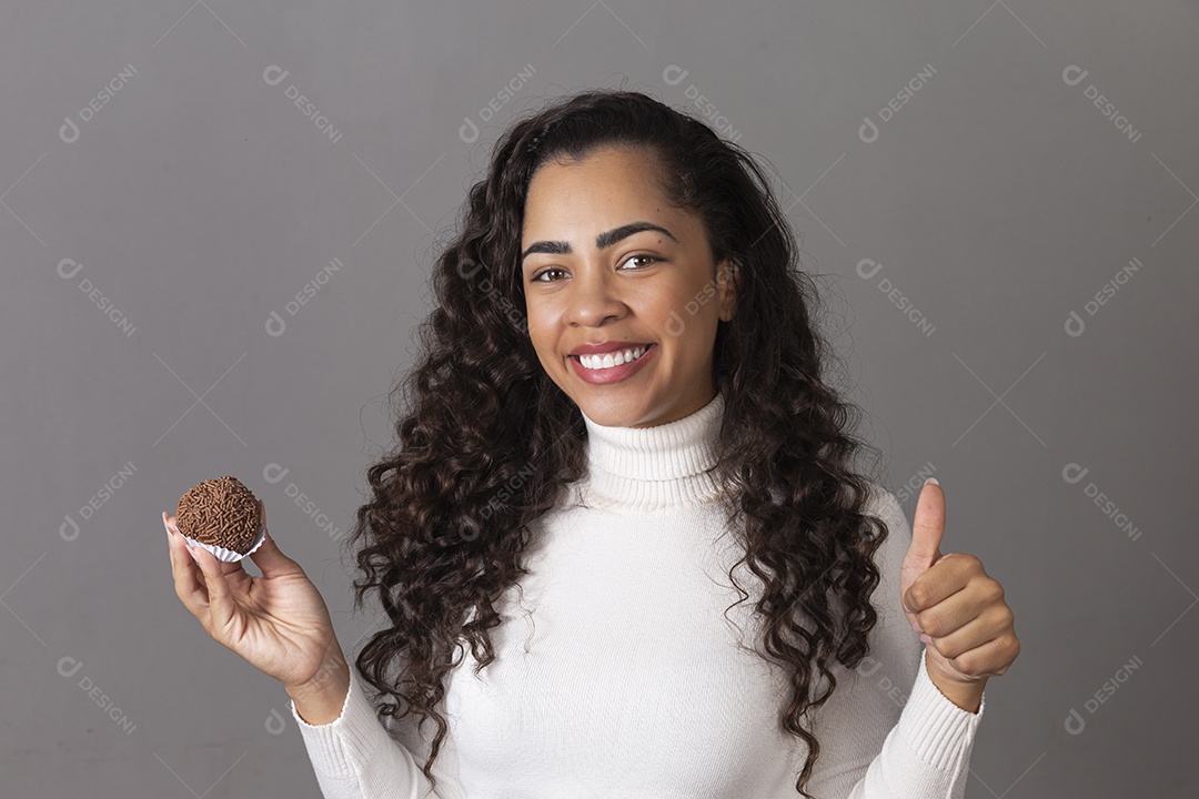 Linda mulher fazendo sinal positivo segurando um cupcake sobre fundo isolado