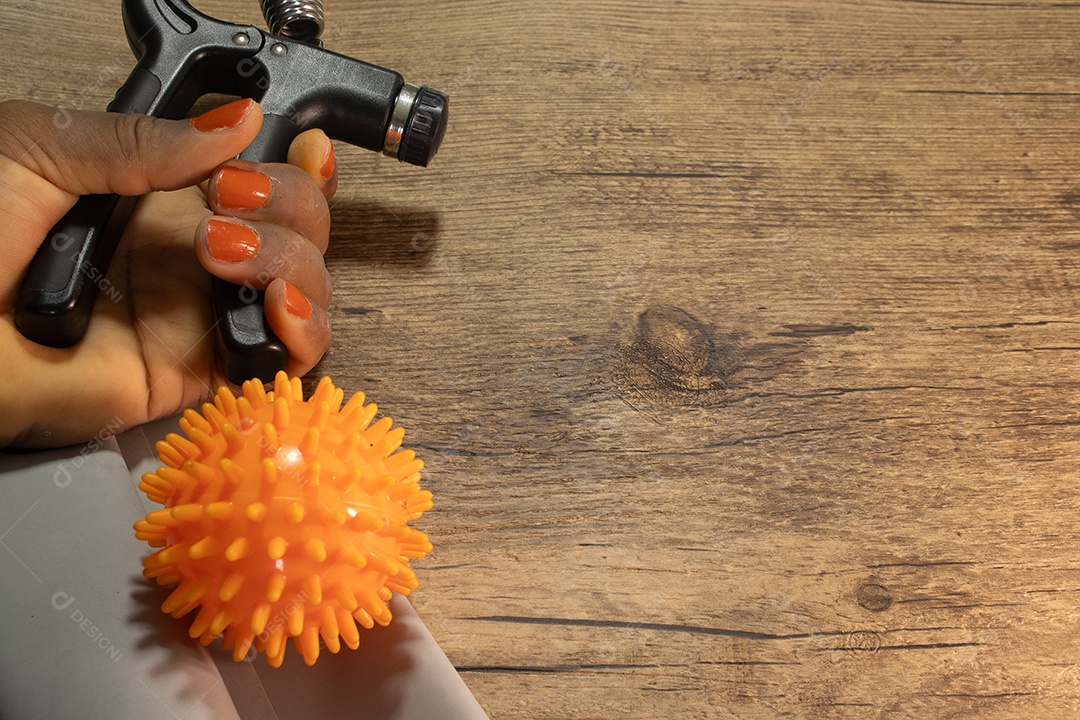 Aperto de mão para exercícios de pulso e cotovelo em uma mesa de madeira