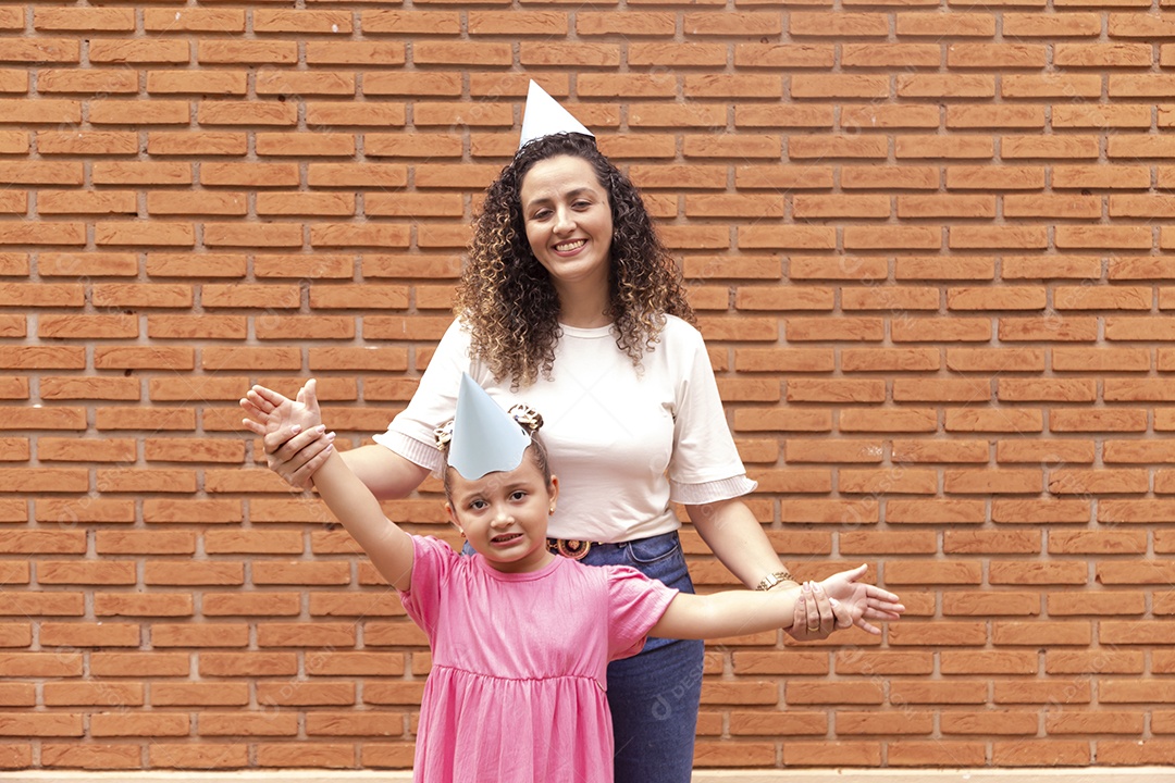 Mãe ao lado de sua filha felizes usando chapéu de aniversário