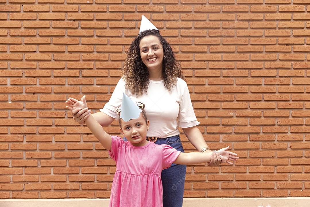 Mãe ao lado de sua filha felizes usando chapéu de aniversário