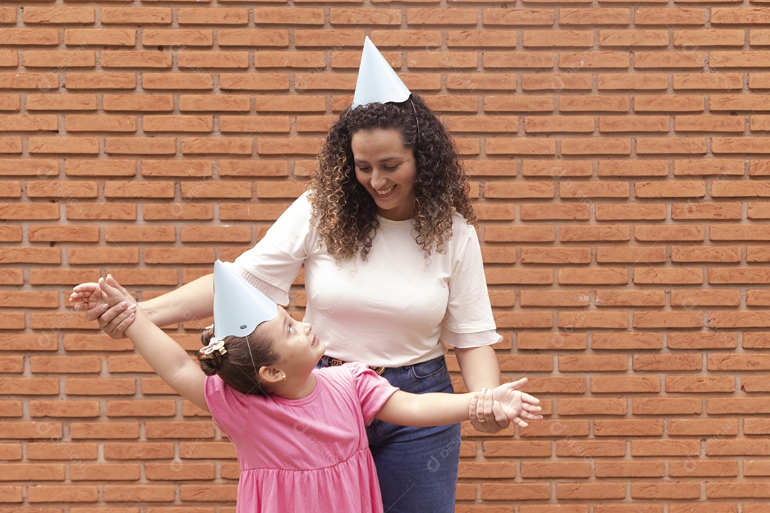 Mãe ao lado de sua filha felizes usando chapéu de aniversário