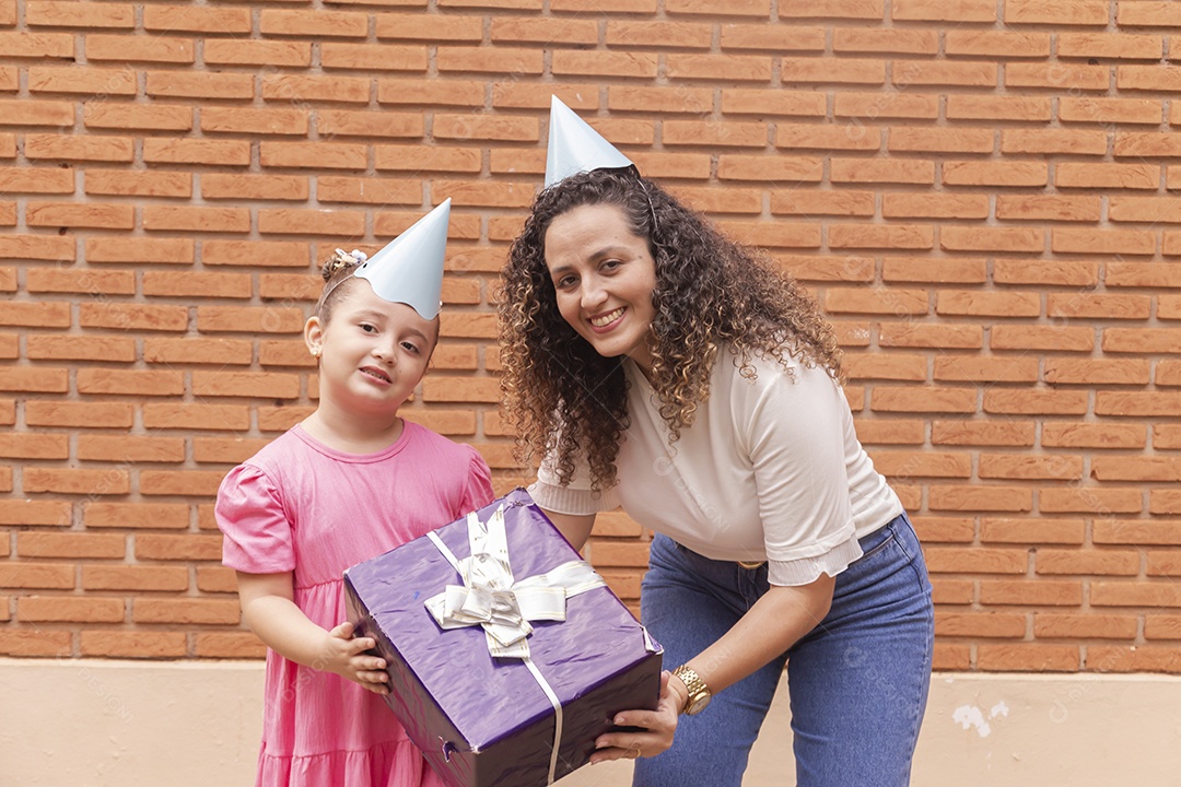 Mãe ao lado de sua filha felizes usando chapéu de aniversário