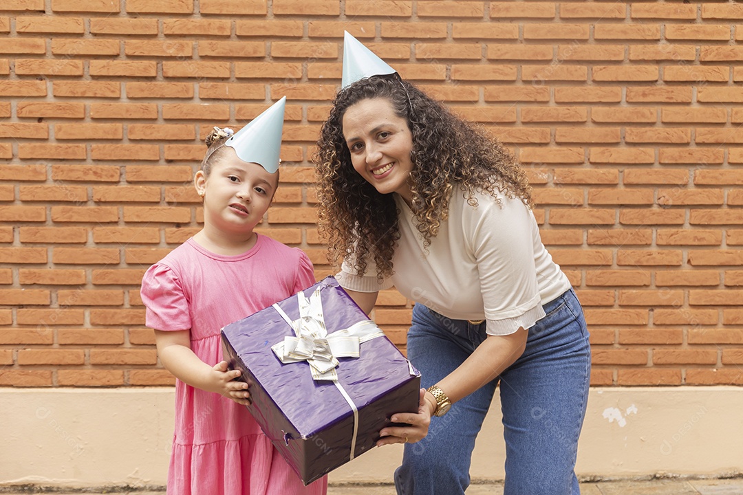 Mãe ao lado de sua filha felizes usando chapéu de aniversário