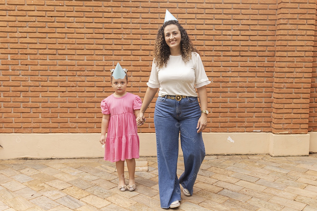 Mãe ao lado de sua filha felizes usando chapéu de aniversário