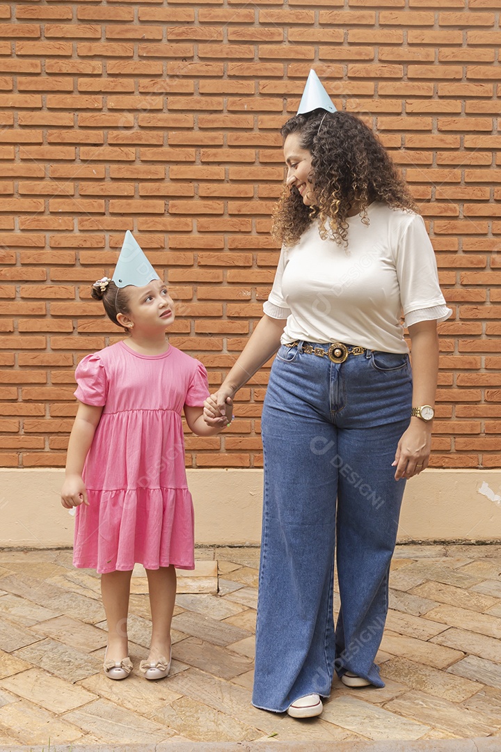 Mãe ao lado de sua filha felizes usando chapéu de aniversário
