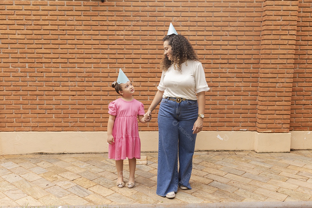 Mãe ao lado de sua filha felizes usando chapéu de aniversário