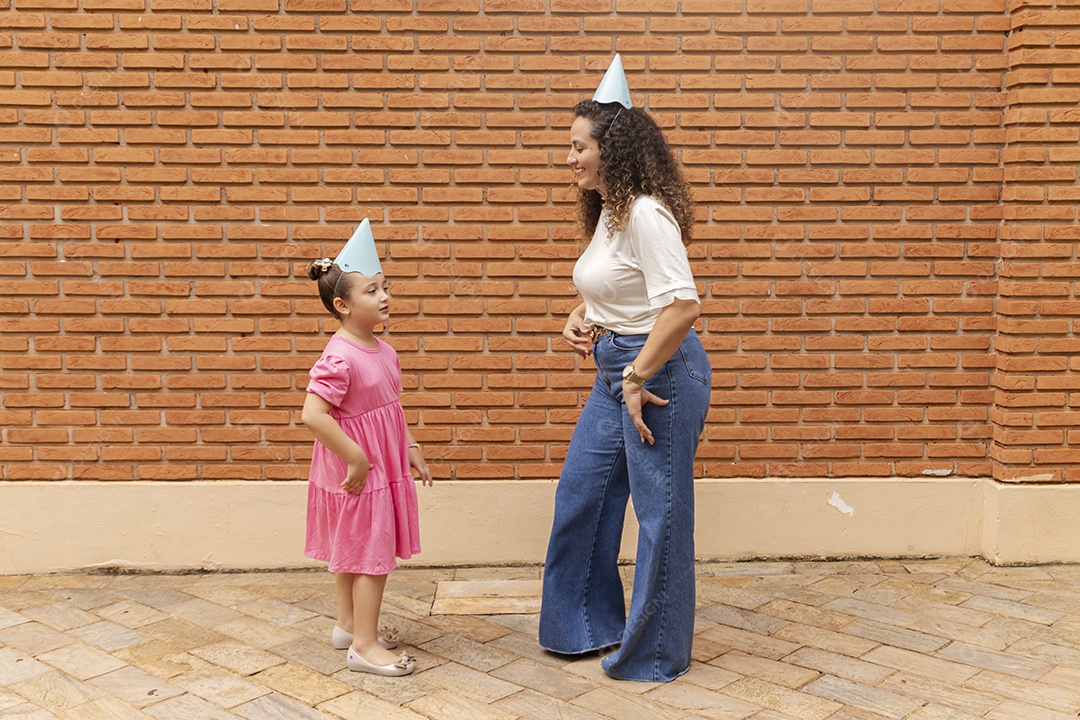 Mãe ao lado de sua filha felizes usando chapéu de aniversário