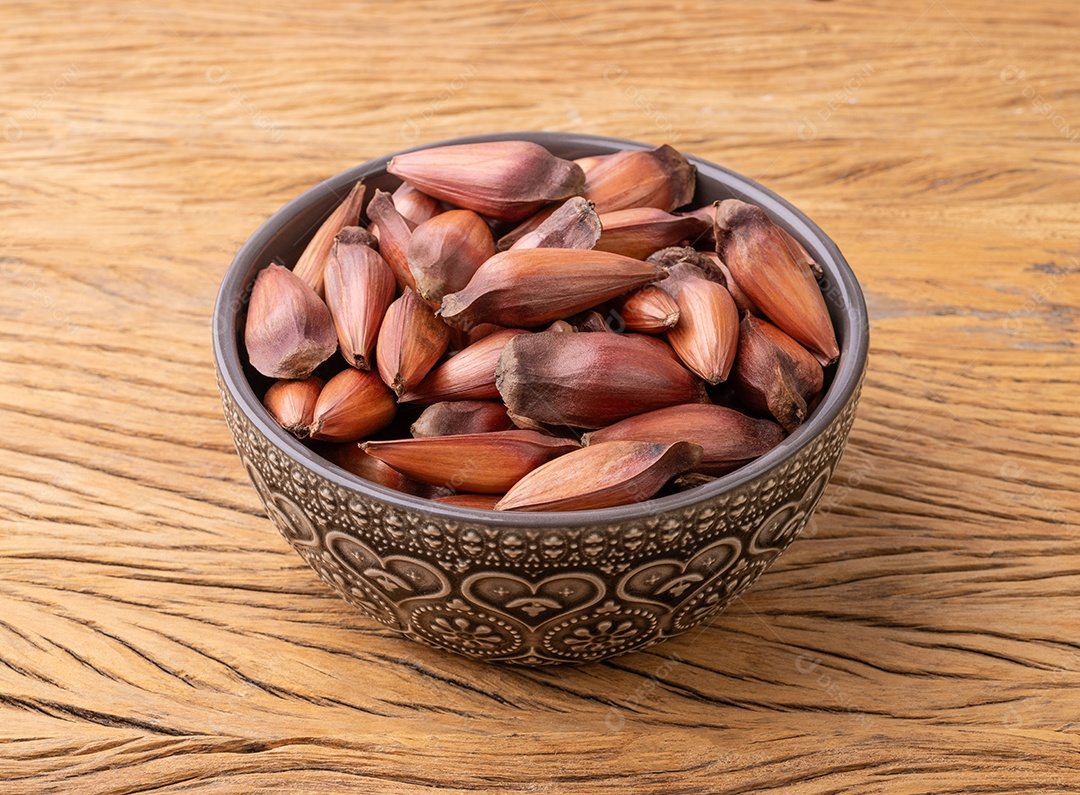 Pinhões ou sementes de pinheiro em uma tigela sobre a mesa de madeira