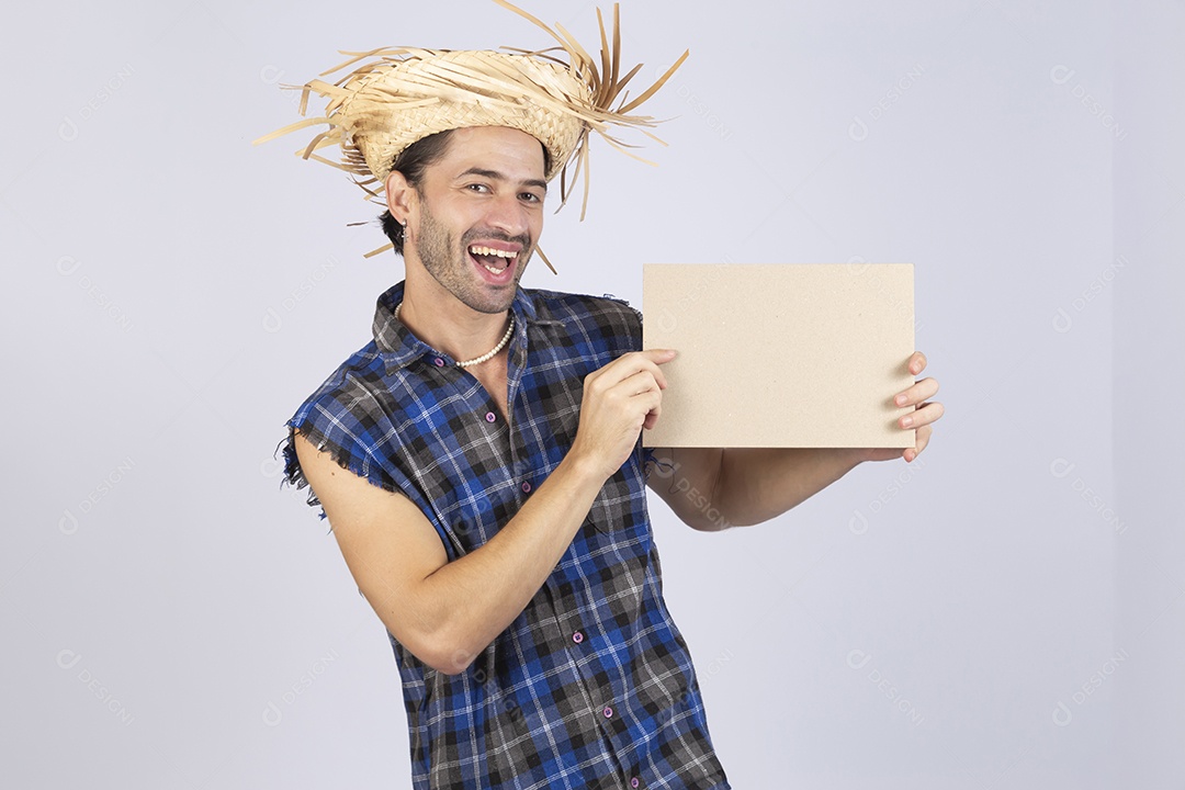 Homem jovem usando roupas típicas de festa junina segurando placa sobre fundo isolado