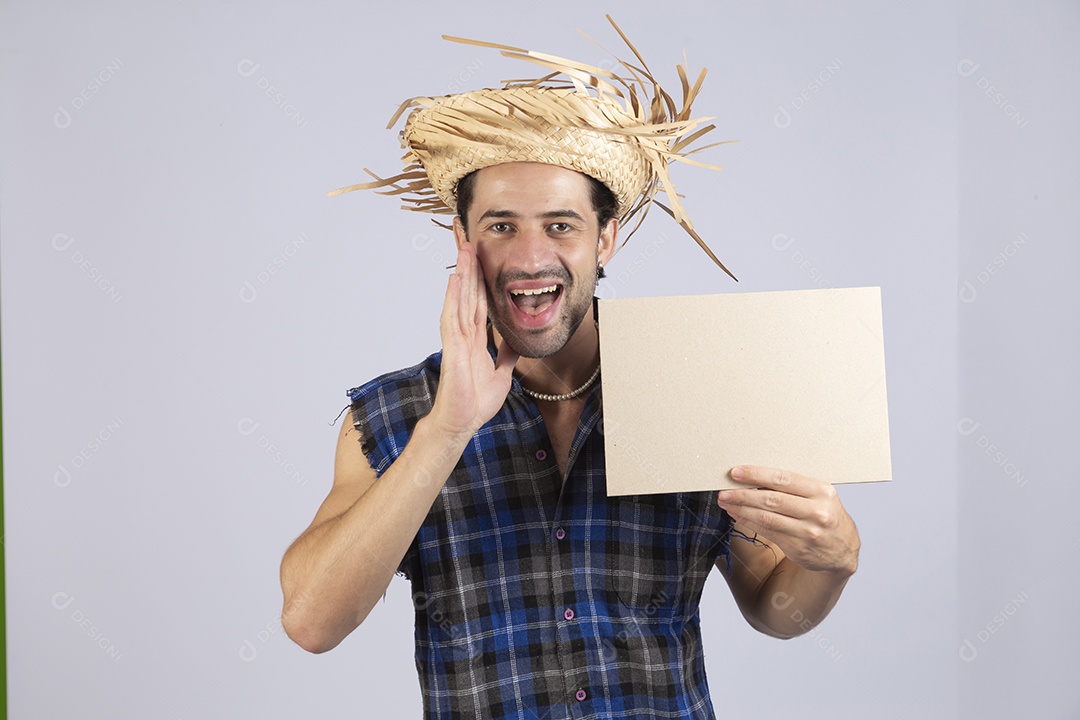 Homem jovem usando roupas típicas de festa junina segurando placa sobre fundo isolado