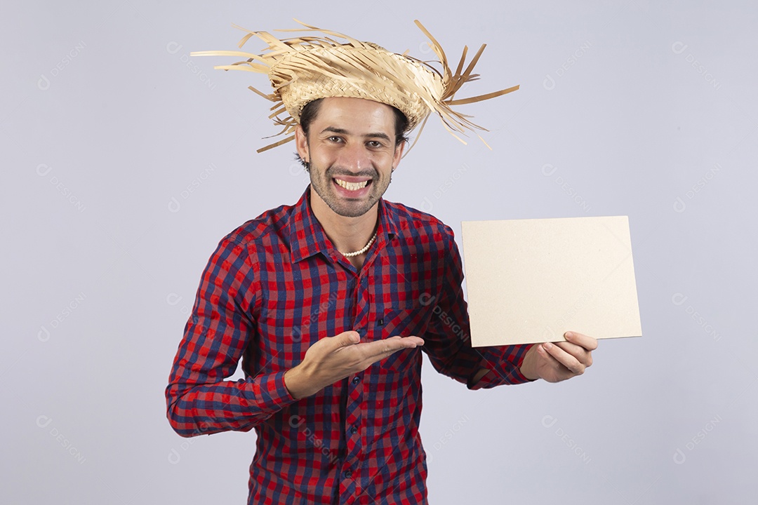 Homem jovem usando roupas típicas de festa junina segurando placa sobre fundo isolado