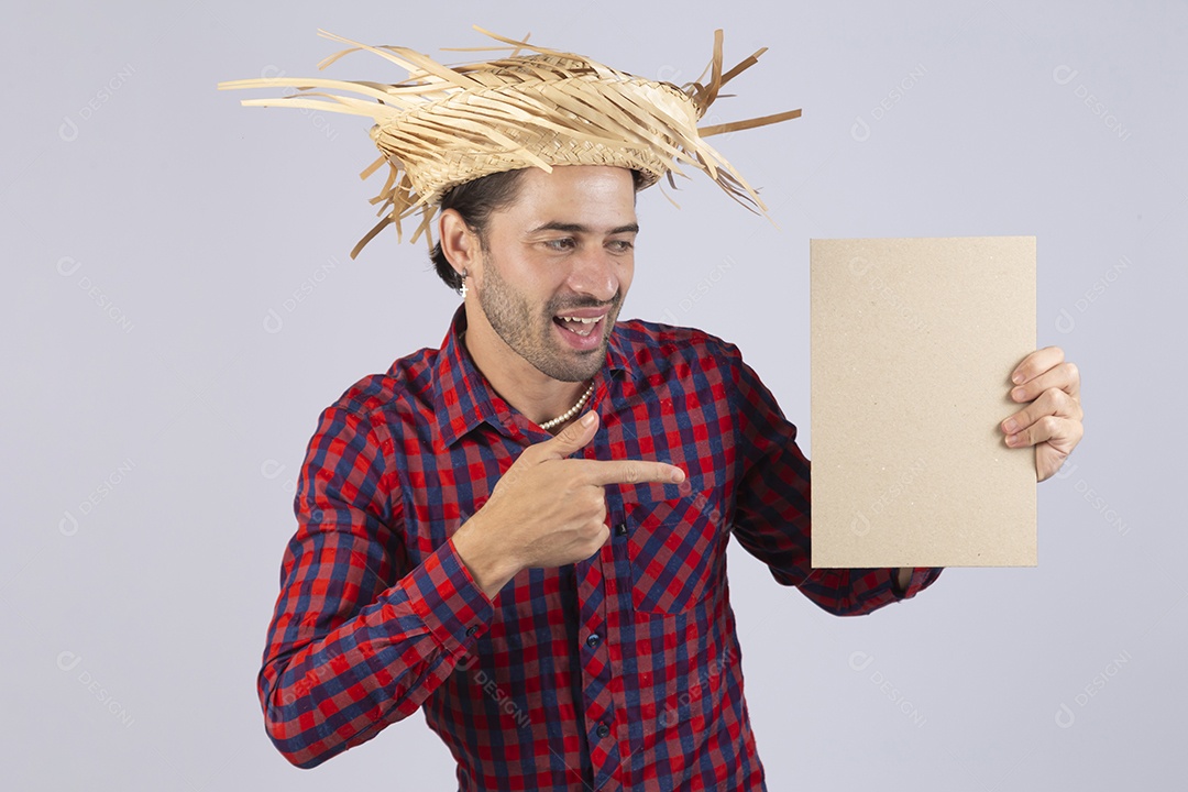 Homem jovem usando roupas típicas de festa junina segurando placa sobre fundo isolado