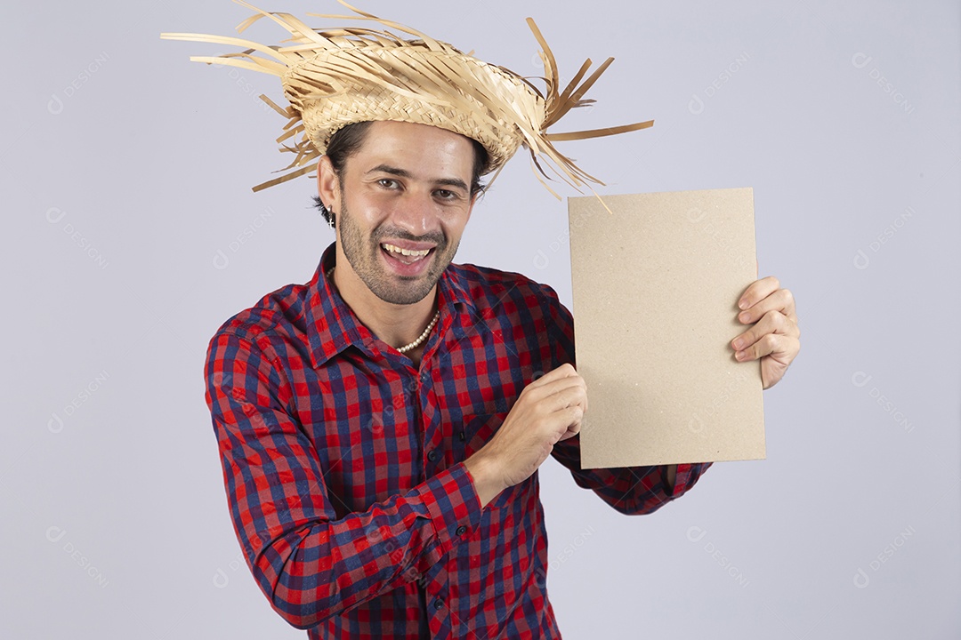 Homem jovem usando roupas típicas de festa junina segurando placa sobre fundo isolado