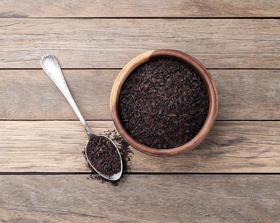 Folhas secas de chá preto em uma tigela sobre a mesa de madeira