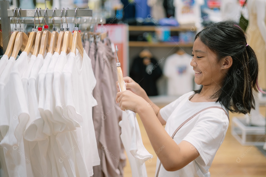 Garota feliz escolhendo roupa na loja