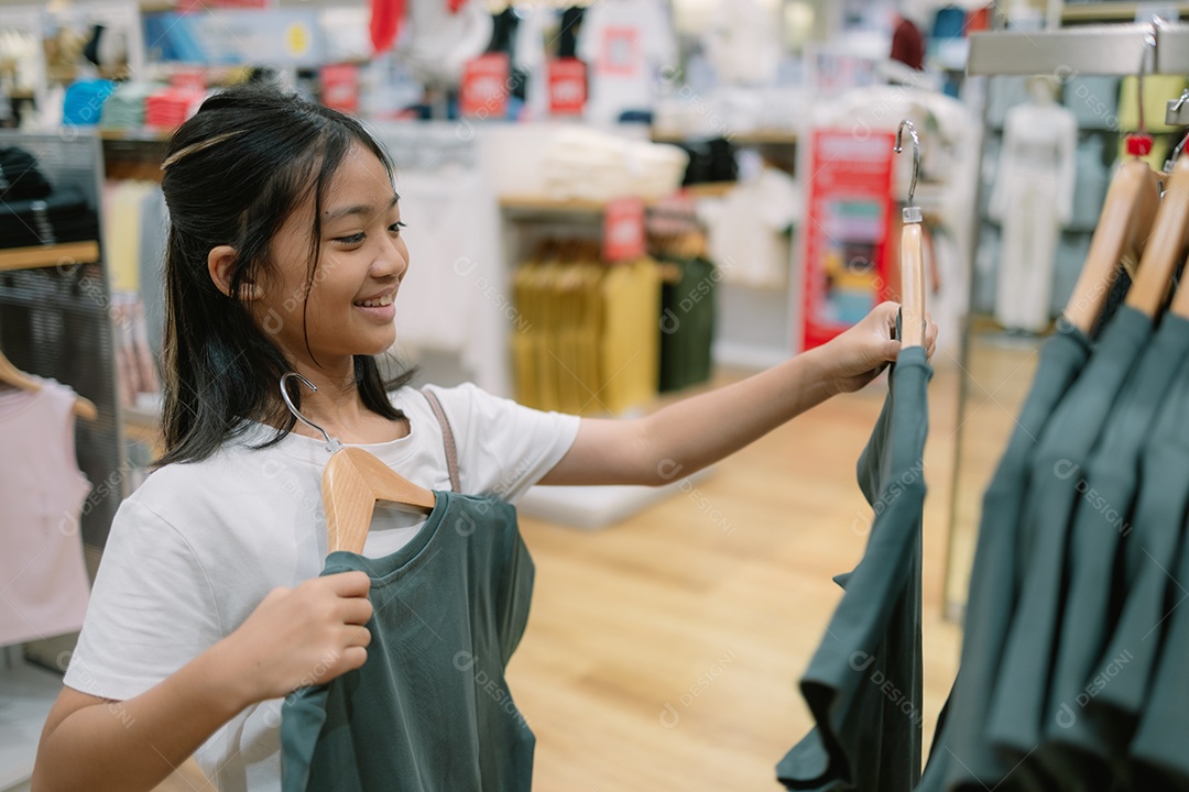 Garota feliz escolhendo roupa na loja