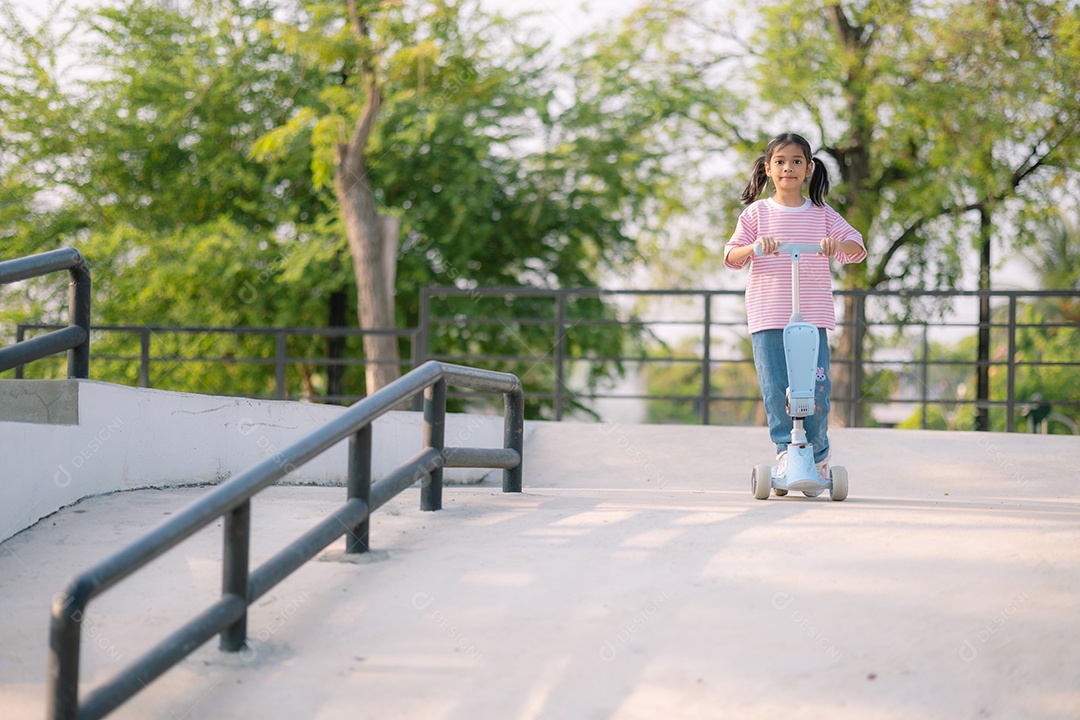 Uma garotinha andando de scooter em um parque