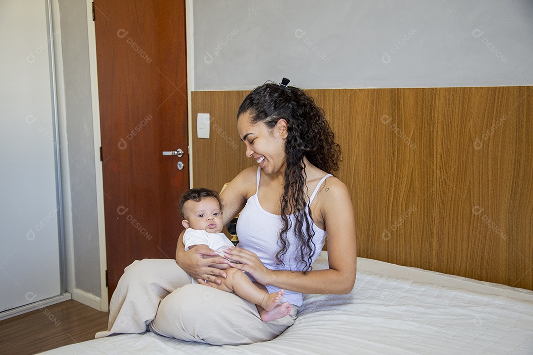 Mãe jovem cuidadando de seu filho sobre quarto