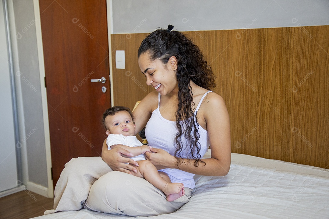 Mãe jovem cuidadando de seu filho sobre quarto