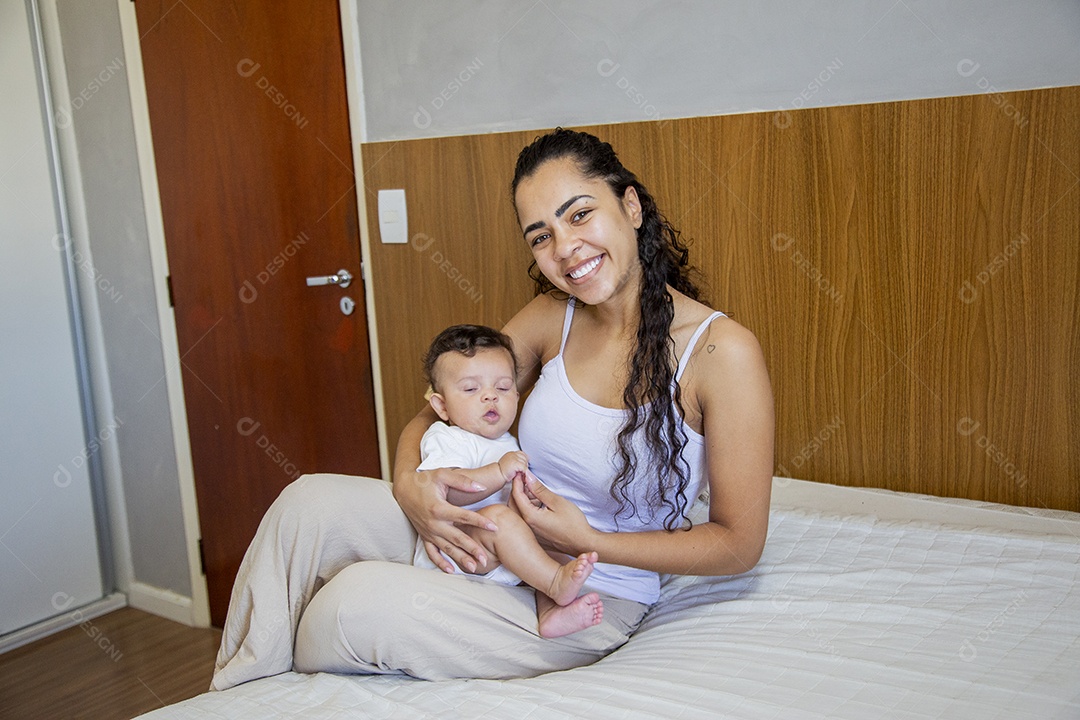 Mãe jovem cuidadando de seu filho sobre quarto