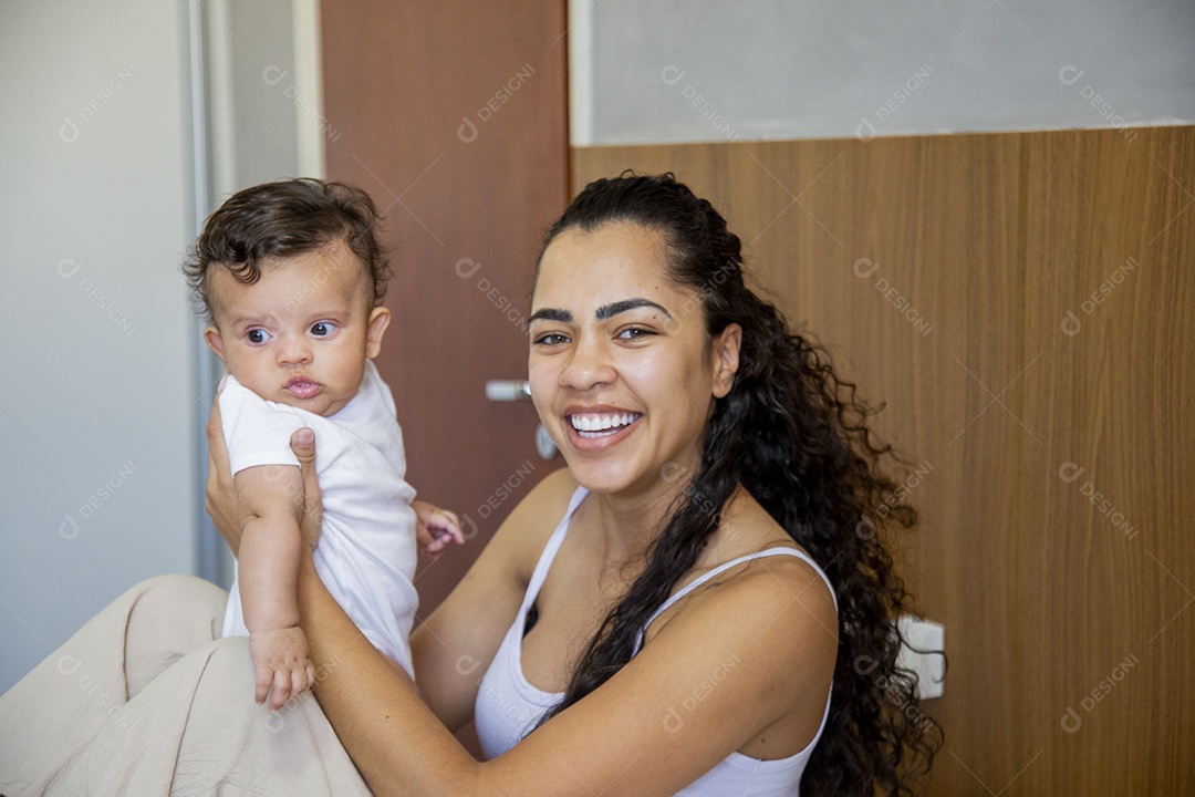 Mãe jovem cuidadando de seu filho sobre quarto