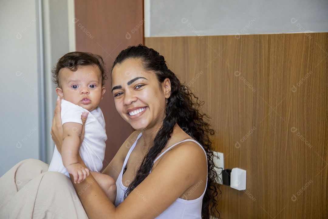 Mãe jovem cuidadando de seu filho sobre quarto