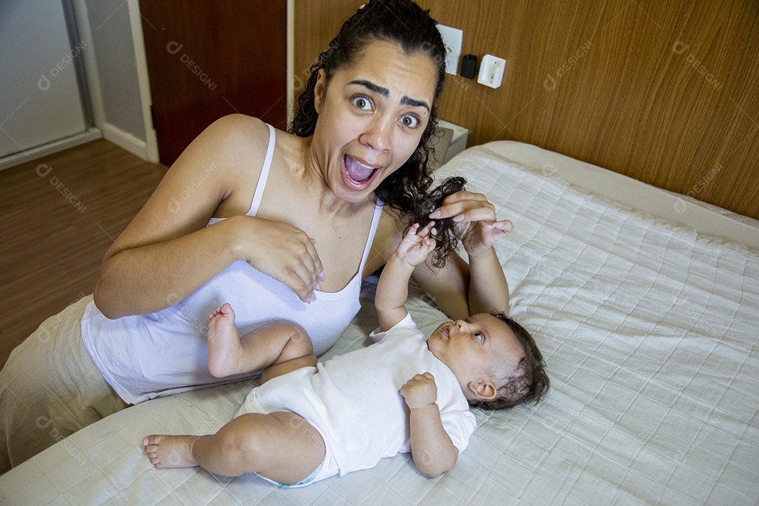 Mãe jovem cuidadando de seu filho sobre quarto