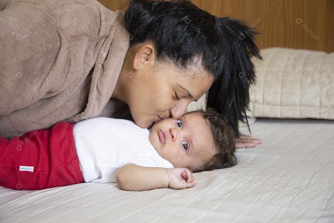 Mãe jovem cuidadando de seu filho sobre quarto