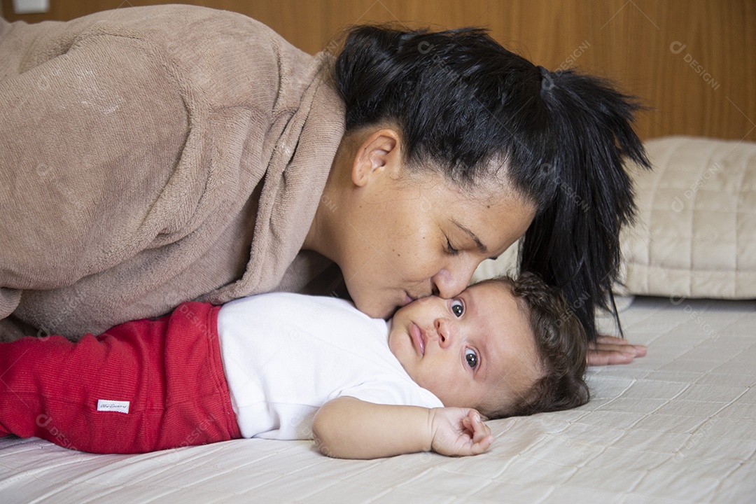 Mãe jovem cuidadando de seu filho sobre quarto