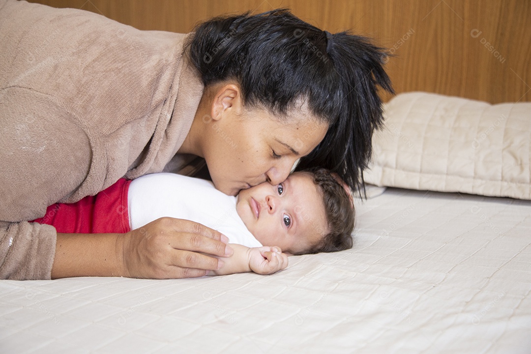 Mãe jovem cuidadando de seu filho sobre quarto