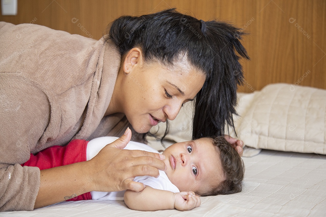 Mãe jovem cuidadando de seu filho sobre quarto
