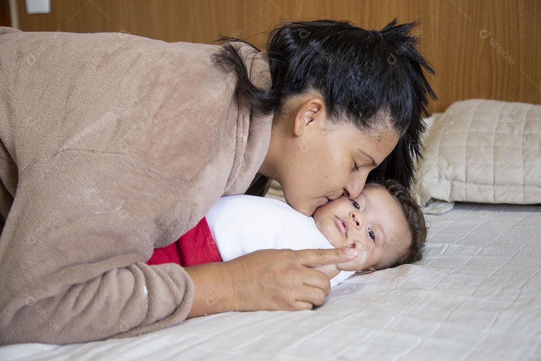 Mãe jovem cuidadando de seu filho sobre quarto