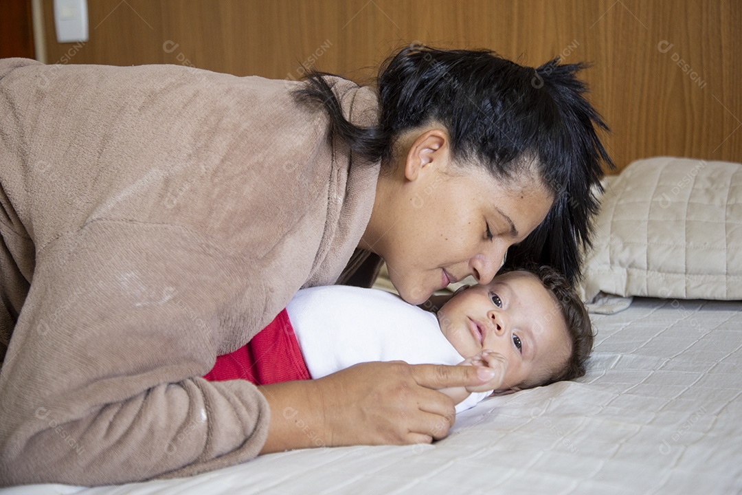 Mãe jovem cuidadando de seu filho sobre quarto