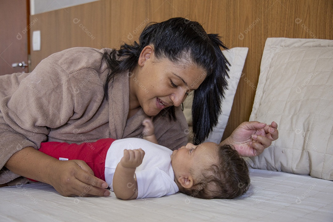 Mãe jovem cuidadando de seu filho sobre quarto