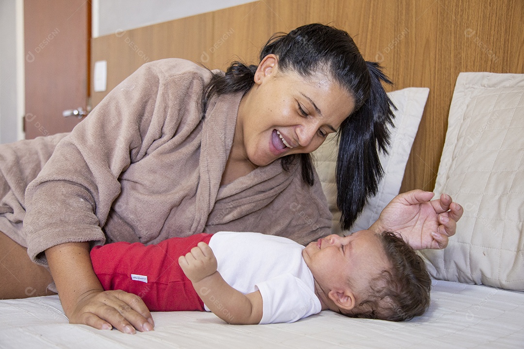Mãe jovem cuidadando de seu filho sobre quarto