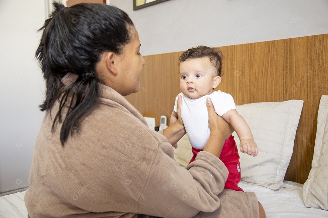 Mãe jovem cuidadando de seu filho sobre quarto