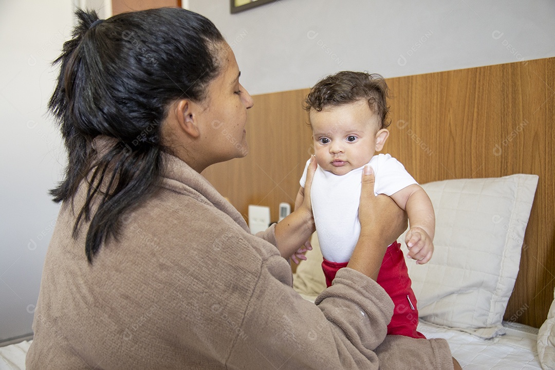 Mãe jovem cuidadando de seu filho sobre quarto