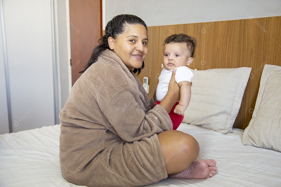 Mãe jovem cuidadando de seu filho sobre quarto