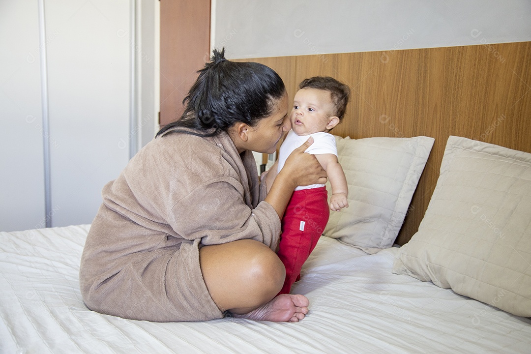 Mãe jovem cuidadando de seu filho sobre quarto