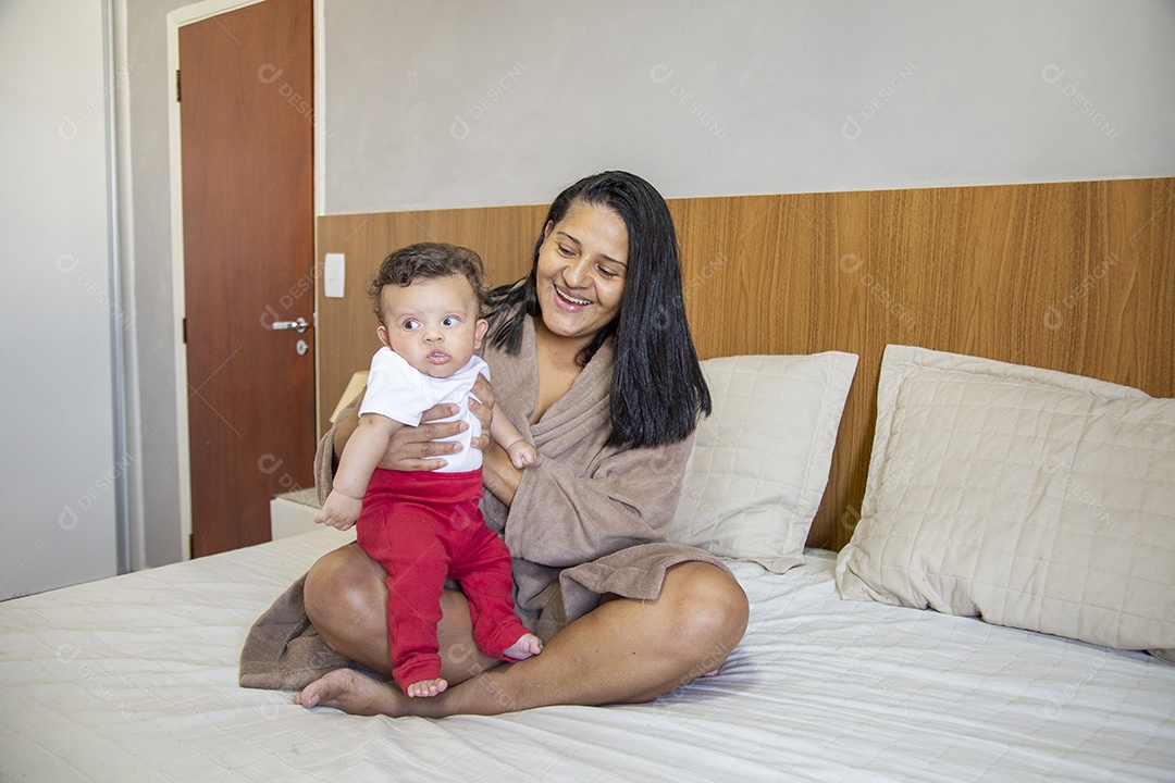 Mãe jovem cuidadando de seu filho sobre quarto