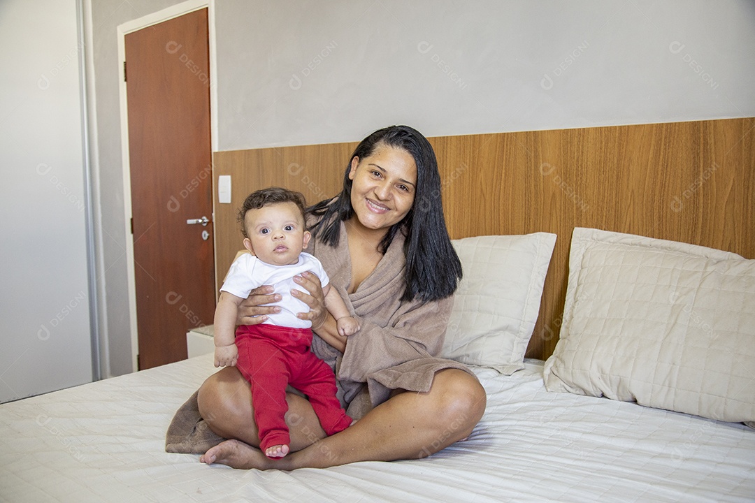 Mãe jovem cuidadando de seu filho sobre quarto