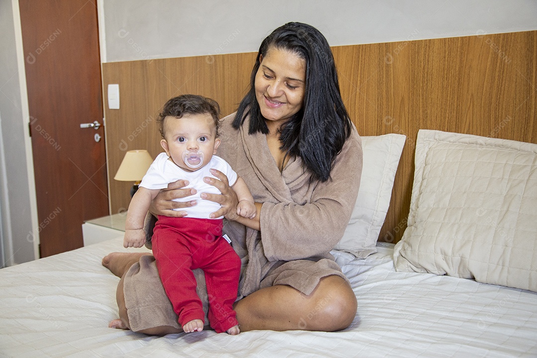 Mãe jovem cuidadando de seu filho sobre quarto