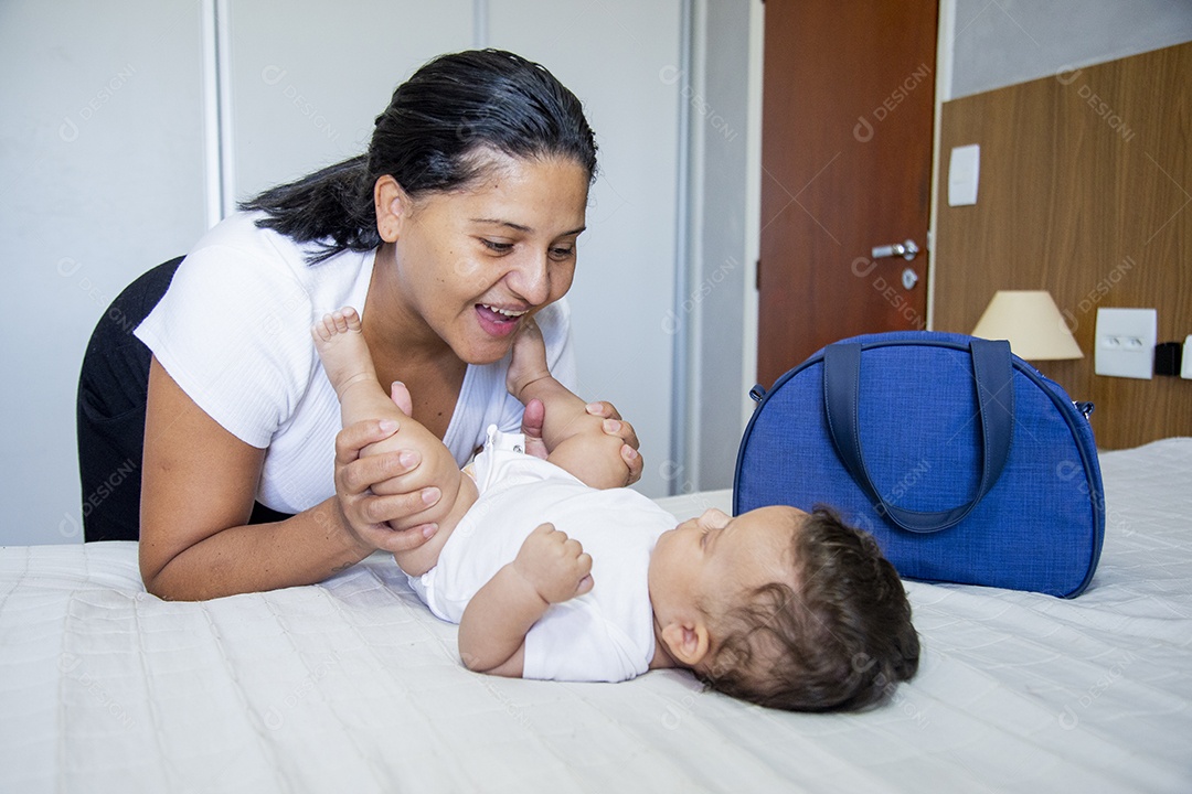 Mãe jovem cuidadando de seu filho sobre quarto