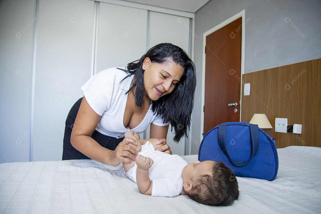 Mãe jovem cuidadando de seu filho sobre quarto