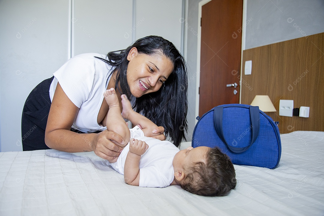 Mãe jovem cuidadando de seu filho sobre quarto