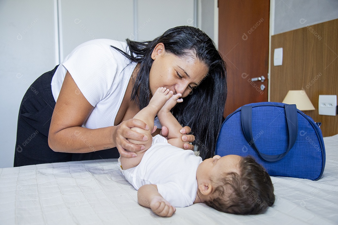 Mãe jovem cuidadando de seu filho sobre quarto